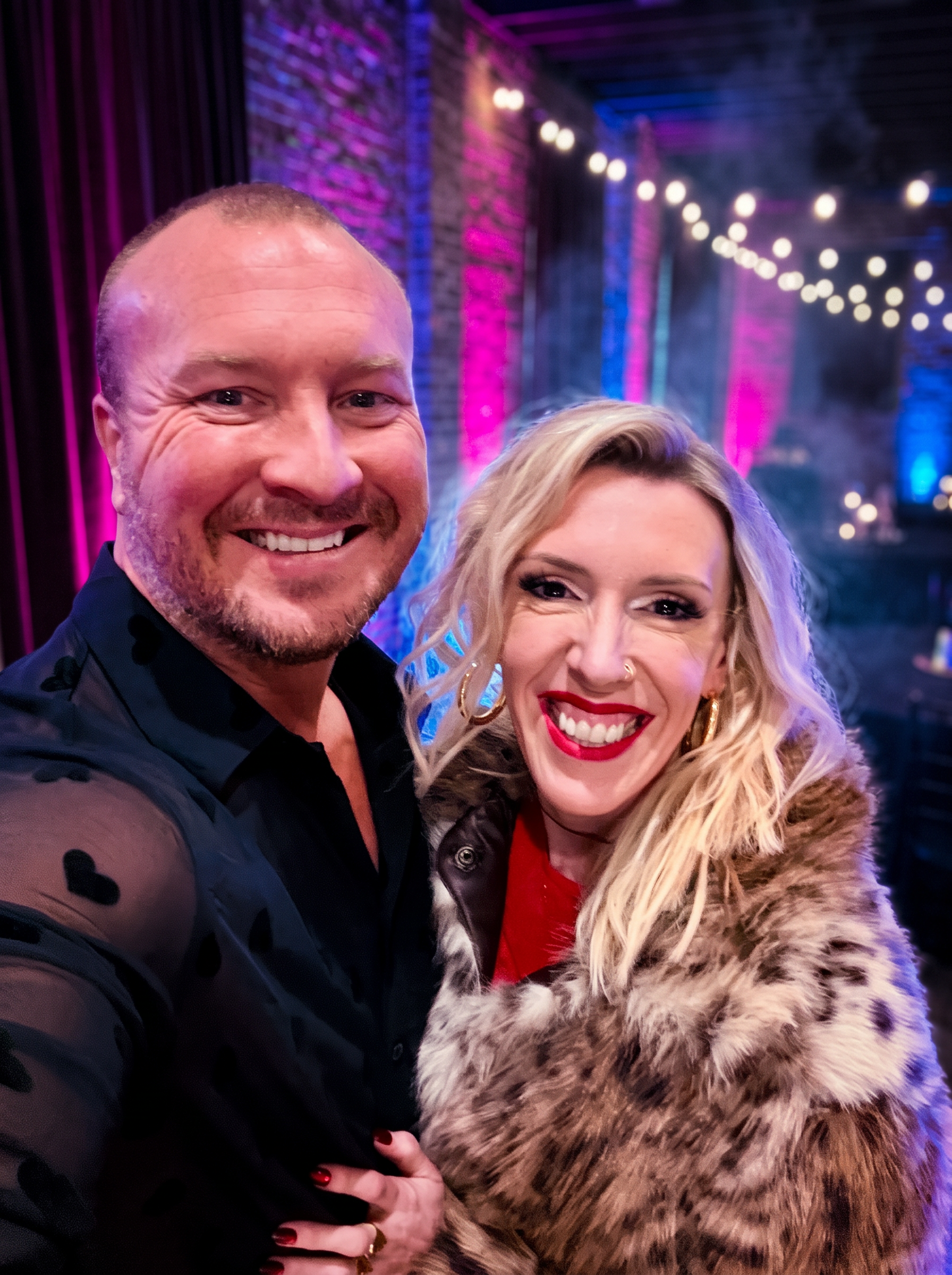 Craig and Dionne Kraus, Portland wedding DJ and photographer duo, at an event with magenta and blue lighting
