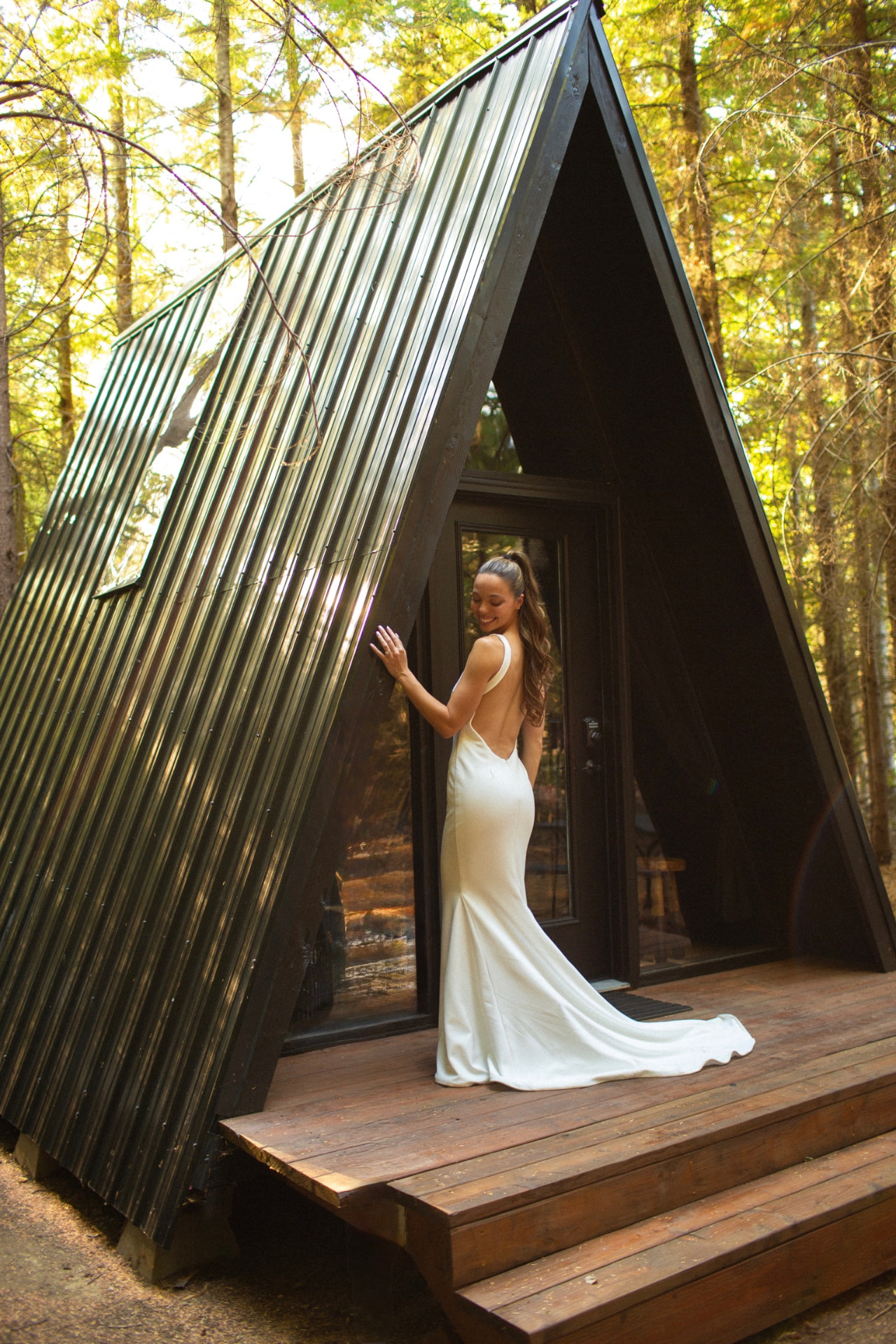 Bride standing on the deck of the black A-frame cabin in the forest at FernHaus
