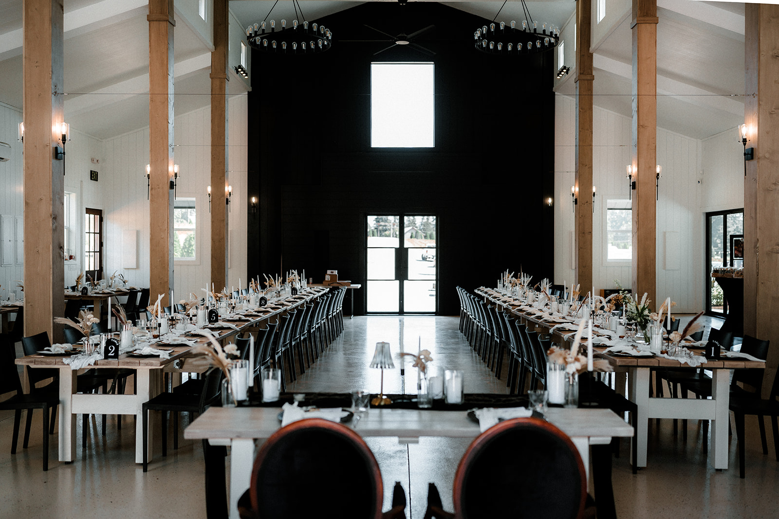 Sage & Social reception hall set for dinner — long farm tables under the black end wall, photographed by Dionne Kraus Photography